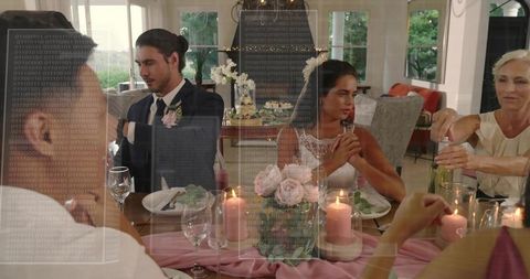 Bride and Groom Sitting at Elegant Reception Table with Floral Centerpiece and Candles