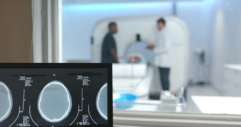 Mri control room monitoring axial brain scans with diverse medical team and patient