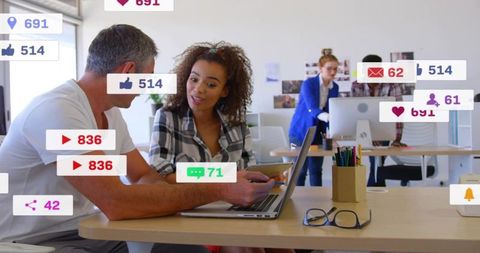 Team Collaborating over Laptop with Social Media Notifications Overlay in Modern Open Office
