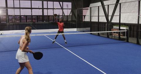 Intense Padel Tennis Rally Between Two Athletes on Indoor Court