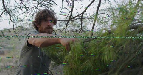 Man Grasping Greenery Exploring Rugged Wilderness