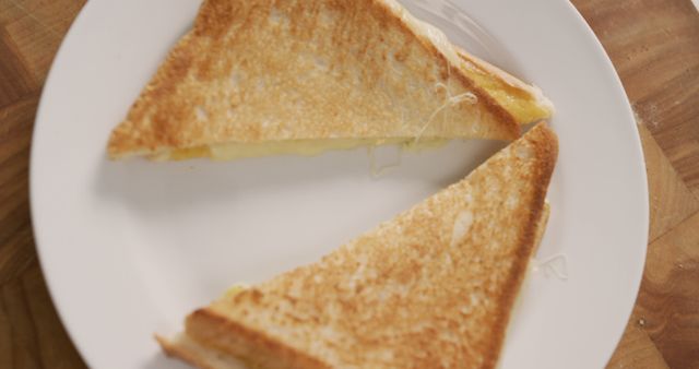 Perfect for use in food blogs, recipe websites, and marketing campaigns for culinary products. Image captures the simplicity and appeal of a classic grilled cheese sandwich, highlighting its crispy texture and gooey melted cheese. It can evoke hunger and satisfaction, pushing its relevance for advertisements or menus in restaurants and cafes.