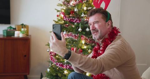 Man Taking Selfie with Christmas Tree in Festive Home Setting