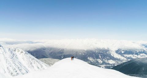 A lone skier stands atop a snowy mountain peak, with copy space - Download Free Stock Photos Pikwizard.com