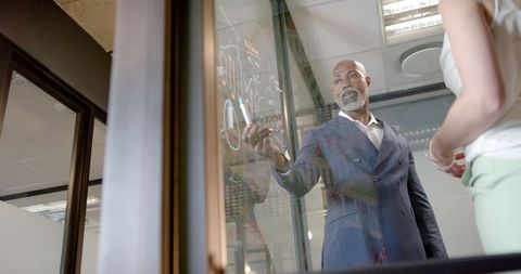 Confident Businessman Presenting Ideas on Office Glass Wall