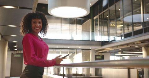 Professional Woman Holding Smartphone in Modern Office Atrium