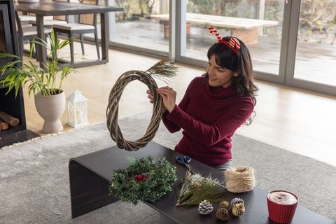 Woman crafting holiday wreath at home