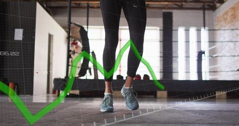 Female athlete jumping on industrial gym floor with green performance chart overlay