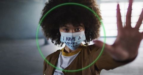 Woman Wearing Message Mask Raising Hand and Signaling Stop in Urban Tunnel with Neon Ring