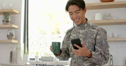 Asian Soldier Checking Phone in Modern Kitchen