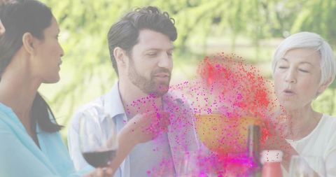 Multigenerational garden gathering celebrating with wine and color powder burst