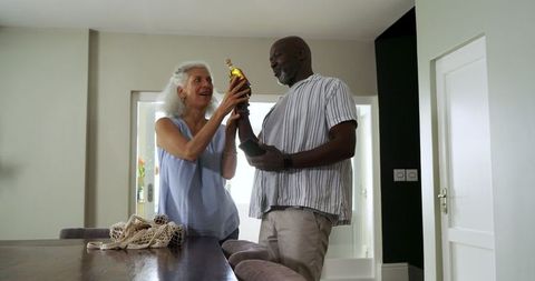 senior couple smiling while examining wine bottle at home - Download Free Stock Images Pikwizard.com