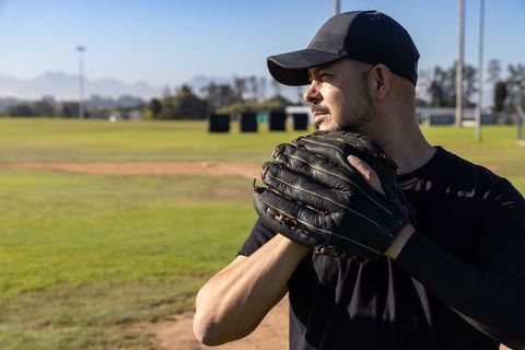 Mature baseball pitcher preparing pitch holding black leather mitt looking toward outfield