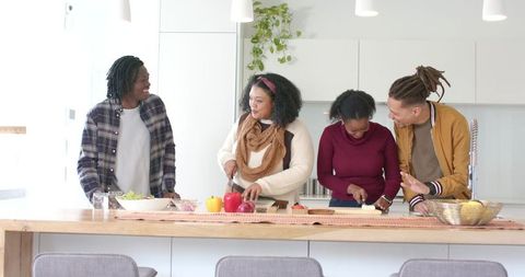 Multiracial Friends Chopping Vegetables on Sunlit Modern Kitchen Island Cooking Together