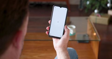 Man Holding Smartphone in Modern Living Room with Coffee Table