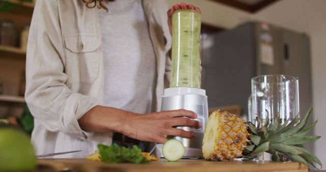 Woman Making Smoothie in Kitchen with Fresh Pineapple and Cucumber - Download Free Stock Images Pikwizard.com