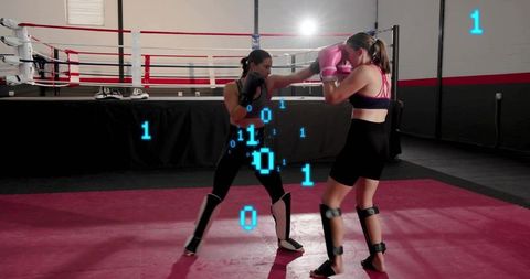 Two women sparring in boxing ring wearing pink gloves and shin guards with blue binary overlay