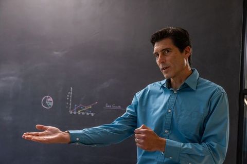 Instructor analyzing data trends on chalkboard during lecture