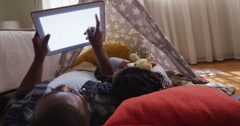 Father and Daughter Bonding with Tablet in Cozy Tent at Home