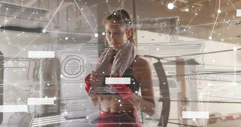 Female boxer analyzing training data with augmented reality overlay in gym ring