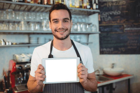 Smiling Barista Holding Transparent Digital Tablet in Cozy Coffee Shop