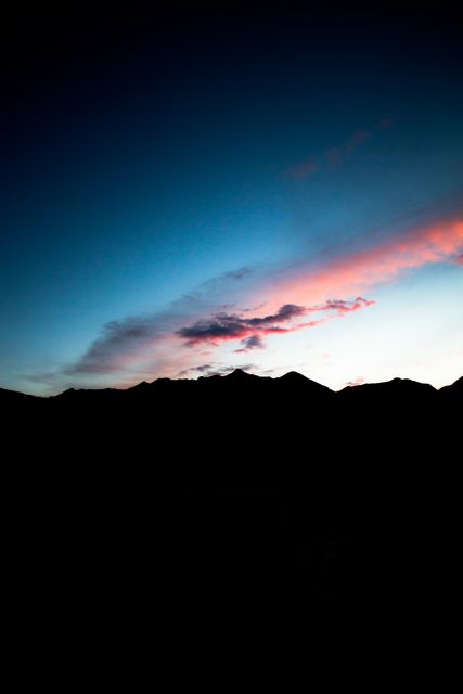 Dramatic mountain range silhouetted against a vibrant and colorful sky at sunset. Stunning mix of blues, purples, and pinks in the sky create a serene and tranquil scene. Ideal for use in travel brochures, nature photography collections, or backgrounds focused on natural beauty and scenic landscapes.