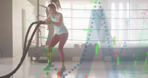 Female athlete swinging battle ropes in boxing ring with fitness hud analytics overlay