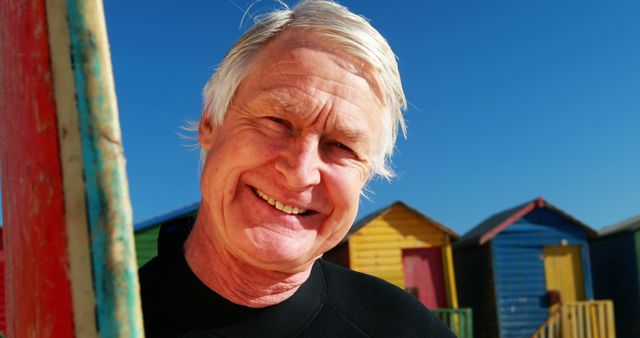 Smiling Senior Man in Front of Colorful Beach Huts on a Sunny Day - Download Free Stock Images Pikwizard.com