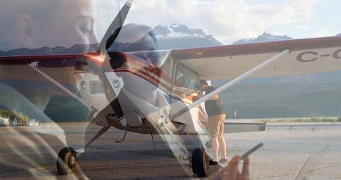 Man inspecting single-engine plane on scenic airstrip at dawn