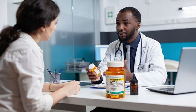 Doctor explaining prescription medication to patient during clinic visit with pill bottle