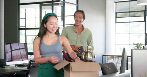 Two colleagues unpacking office items together joyfully