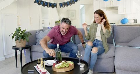 Mature Couple Enjoying Humorous Birthday Celebration on Sofa