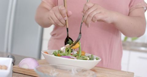 Plus Size Woman Preparing Fresh Salad in Modern Kitchen
