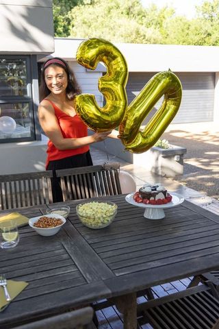 Woman Celebrating 30th Birthday Outdoors with Cake and Balloons