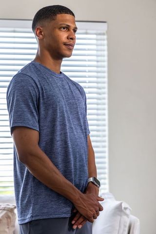 Young man controlling smart blinds with smartwatch in modern minimalist living room