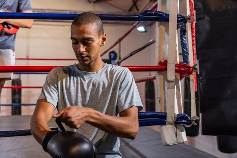African american boxer adjusting glove in ring preparing for training session