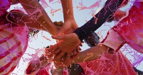Teammates placing stacked hands in huddle outdoor with red jerseys and geometric overlay