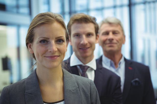 Businesswoman standing confidently in front of her team in a modern office environment. Ideal for use in corporate websites, business presentations, leadership articles, and professional networking profiles.