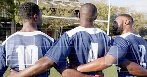 Linking arms: three team players standing together on grass wearing navy jerseys 10 4 2