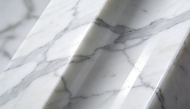 Polished white marble slab featuring angled ridges and soft gray veining