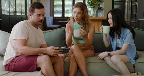 Diverse Friends Engaging with Smartphone in Cozy Living Room