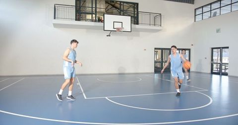 Athletic teammates playing basketball in modern indoor facility