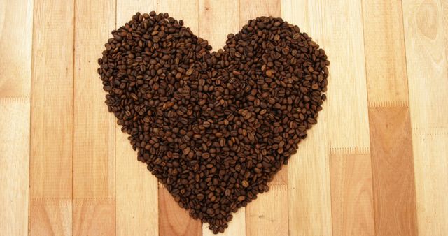 Coffee beans are arranged in a heart shape on a wooden surface, symbolizing a love for coffee. This creative display merges the warmth of wood with the rich tones of the beans, evoking a cozy, aromatic atmosphere.