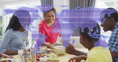 Multigenerational family serving fresh salad and sharing warm meal with world map overlay