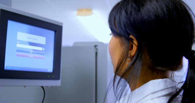 Female scientist working in a modern laboratory with touchscreen computer, possibly entering or accessing data. Suitable for illustrating technology in scientific research, healthcare advancements, and lab technician activities.