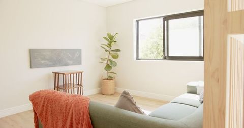 Minimalist living room with green sofa and orange throw blanket