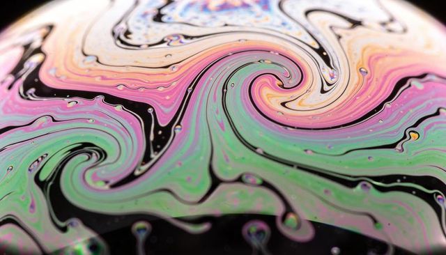 Swirling iridescent soap film creating pastel vortex with black channels, macro texture