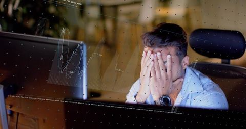 Stressed trader covering face at desk with market charts, analytics and dashboard overlays