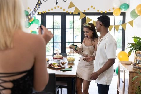 Surprised Birthday Woman Opening Gift During Indoor Celebration