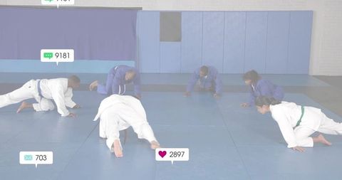 Martial artists crawling across dojo mat during group conditioning training wearing gis